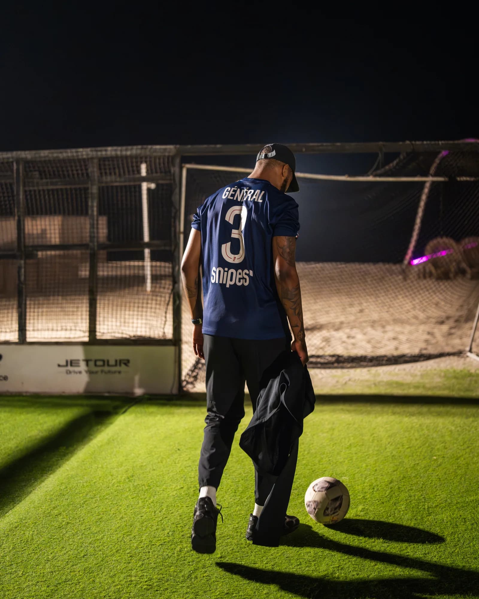 Kimpembe walks toward the ball on a floodlit desert pitch, 'Général' emblazoned across his PSG shirt.