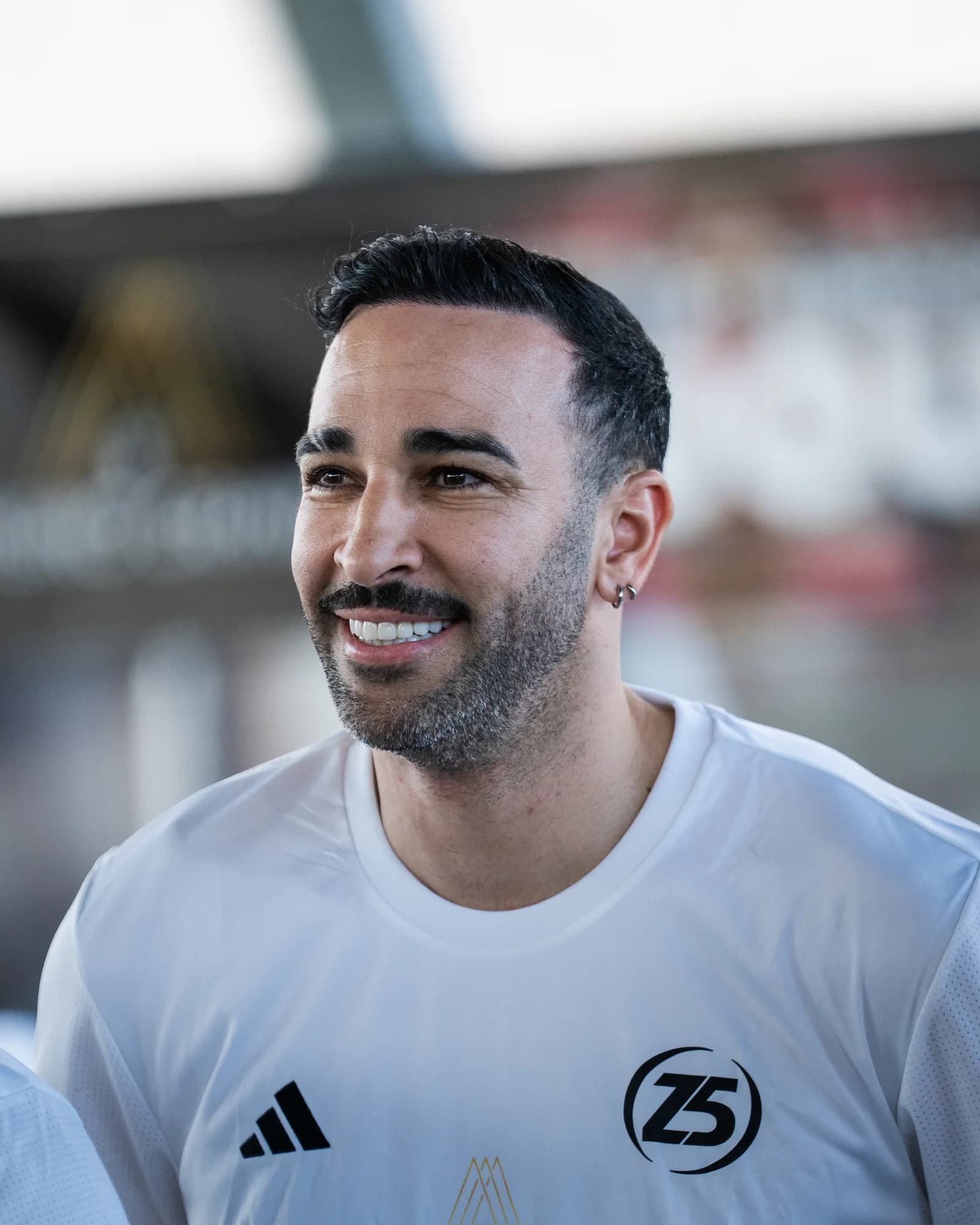 Adil Rami beams in his white Z5 jersey, caught in a warm candid portrait at the Stars Cup.
